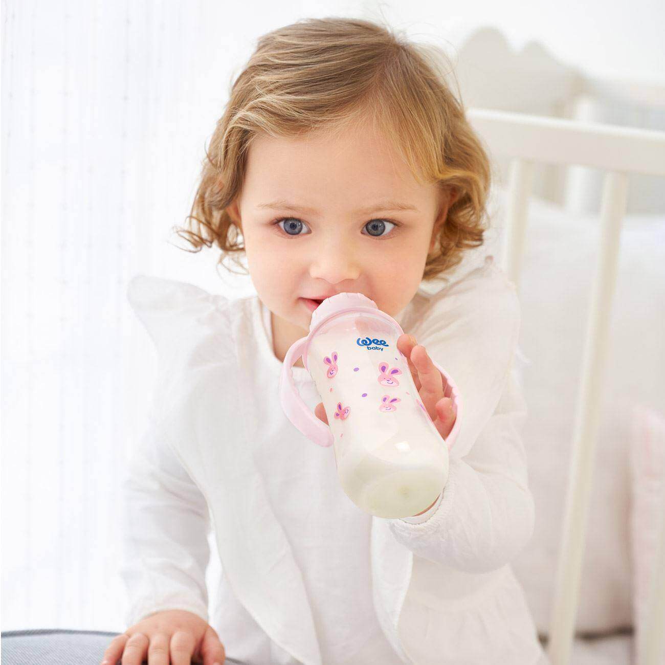 a little girl that is holding a pink toothbrush 